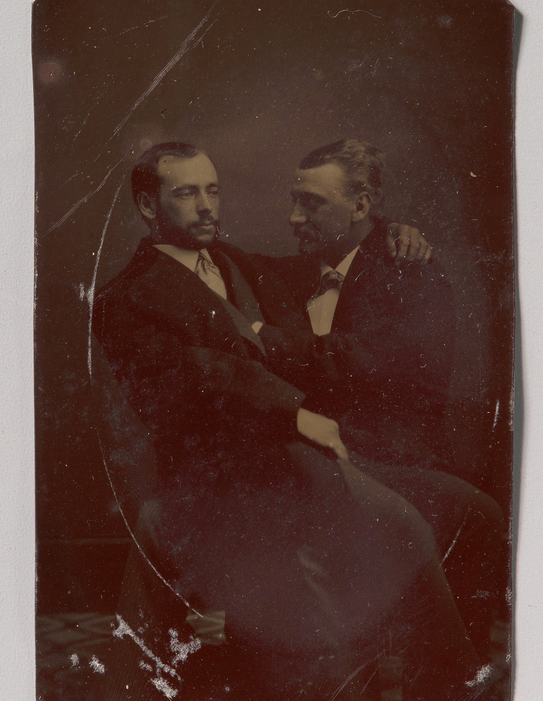 Двое мужчин сидят, один на коленях у другого, с руками в намёкающих позах; тинтайп, фотография неизвестного автора, 1880-е годы