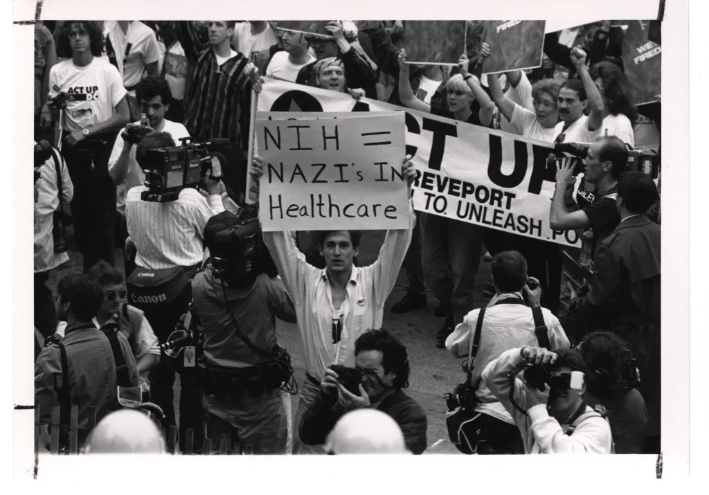 Aktivisten der Bewegung ACT UP bei einem Protest vor den Nationalen Gesundheitsinstituten der USA im Mai 1990. Foto: [NIH History Office / Wikimedia Commons](https://commons.wikimedia.org/wiki/File:ACT_UP_Activists_at_the_National_Institutes_of_Health_(14359361475).jpg) (Public domain)