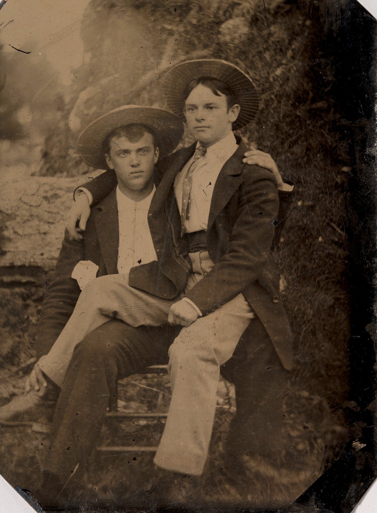 Dois jovens com chapéus de palha, um sentado no colo do outro; ferrotipia de autor desconhecido, décadas de 1870–1880