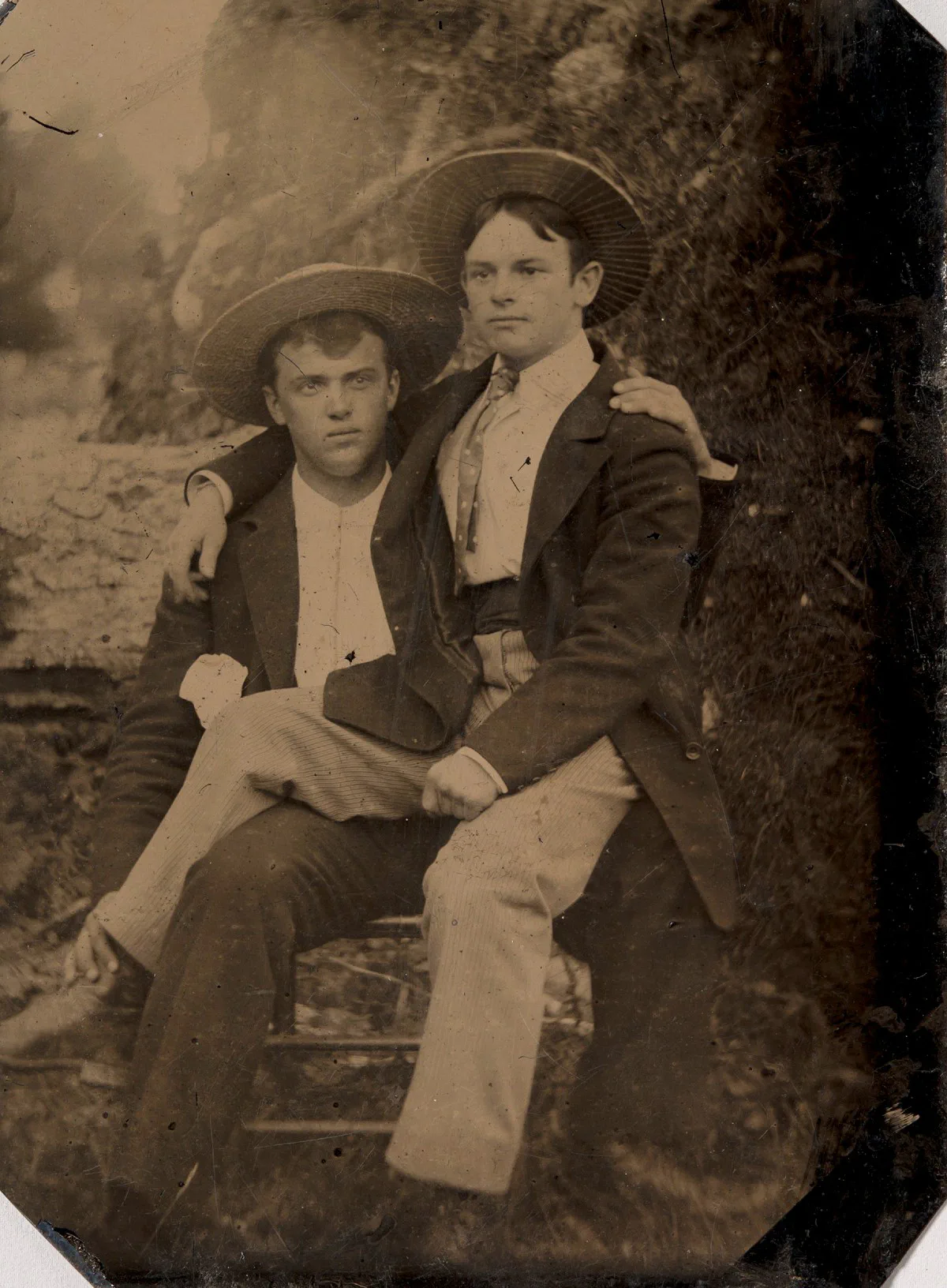 Due giovani uomini con cappelli di paglia, uno seduto in braccio all’altro; ferrotipo, autore sconosciuto, anni 1870-1880