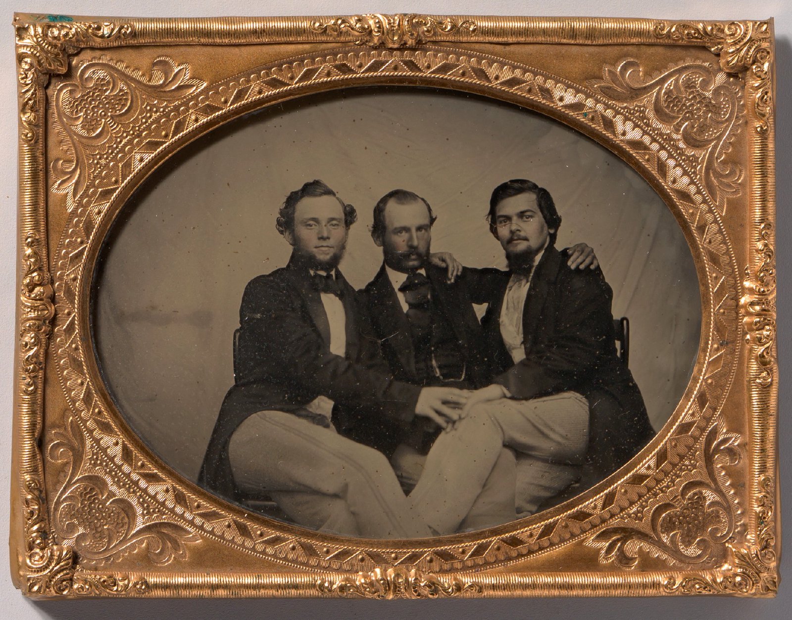 Três homens sentados, abraçados pelos ombros; ambrótipo de autor desconhecido, década de 1860