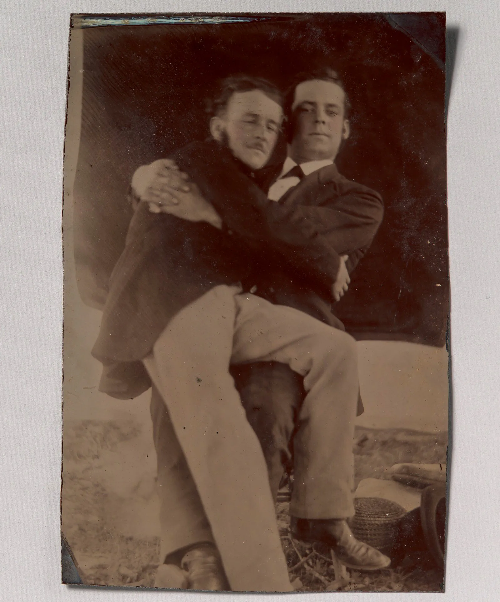 Due uomini abbracciati, uno seduto in braccio all’altro; ferrotipo, autore sconosciuto, anni 1880-1890