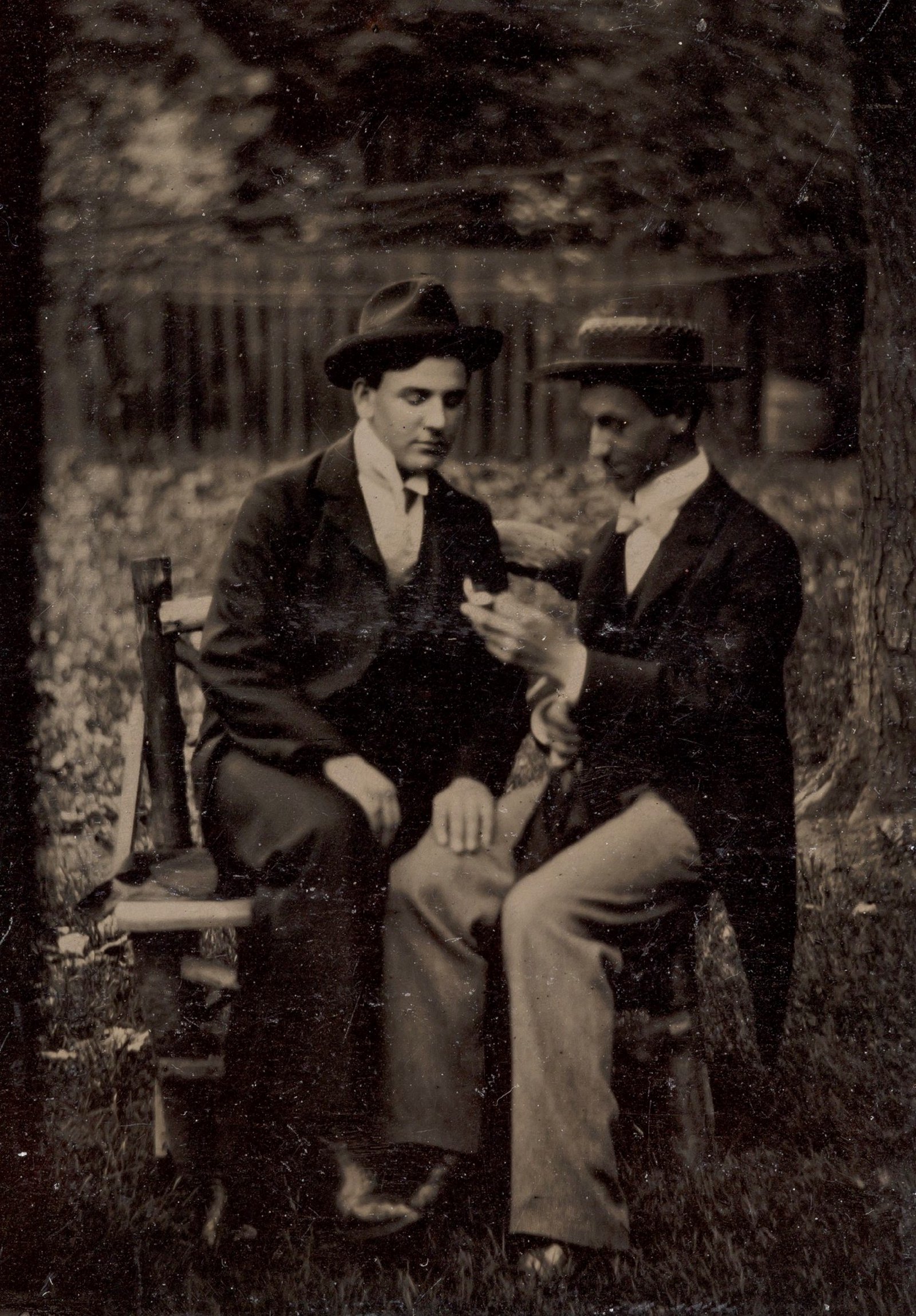 Dois homens sentados num banco, um com a mão na perna do outro; ferrotipia de autor desconhecido, décadas de 1870–1880