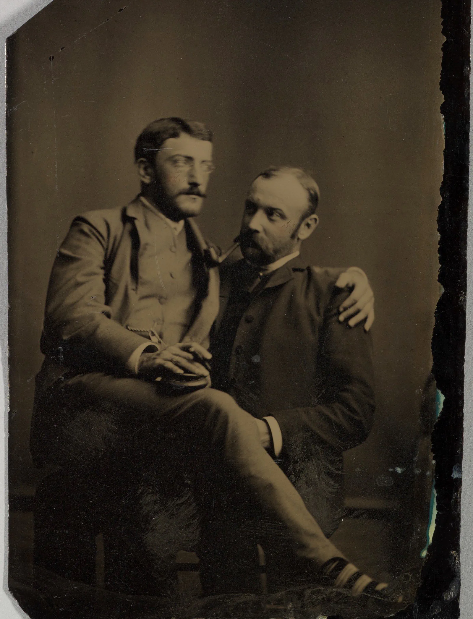 Due uomini che fumano, uno seduto in braccio all’altro; ferrotipo, autore sconosciuto, anni 1880-1890
